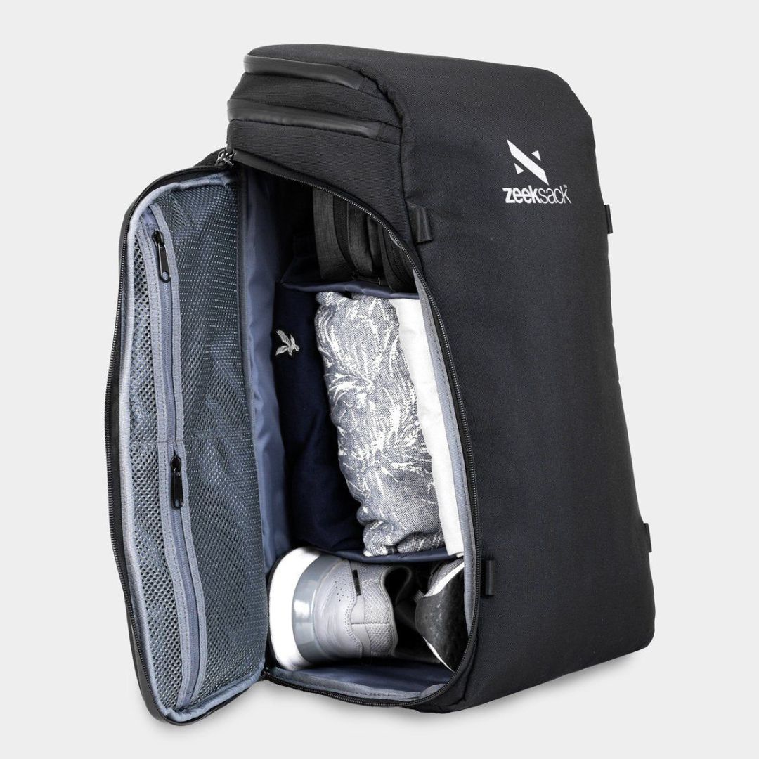 Musta reppu avattu sivulta, pakattu kengillä ja vaatteilla.