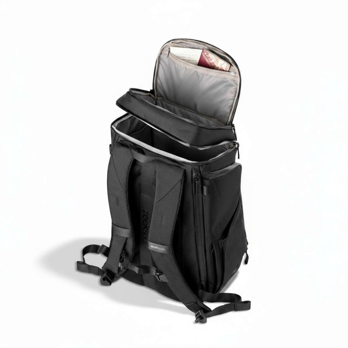 Musta reppu sivulta, seisoo lattialla ja ylin lokero on osittain auki.