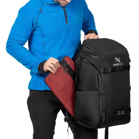 Mies ottaa kannettavan tietokoneen ulkoisesta sivutaskusta Zeeksack-repussa.