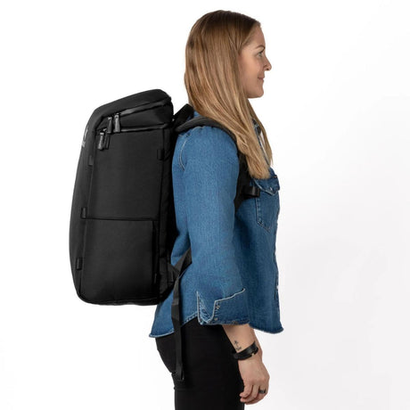 Nainen seisoo sivuprofiilissa ja kantaa mustaa Zeeksack-reppua.