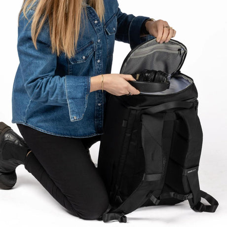 Nainen laittaa kuulokkeet Zeeksack-repun yläosassa olevaan pikkutaskuun.