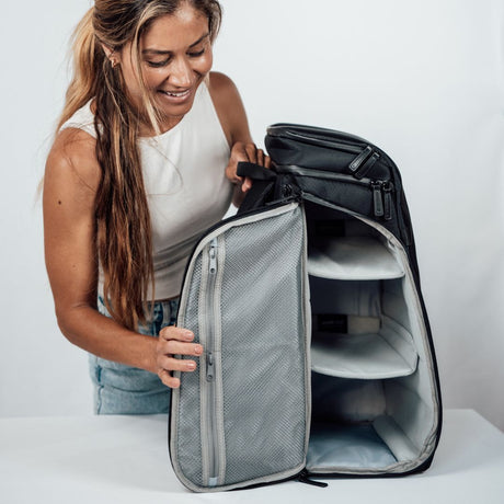 Nainen pakkaa Zeeksack-reppua pöydällä, reppu täysin auki ja järjestetty sisältö näkyvissä.